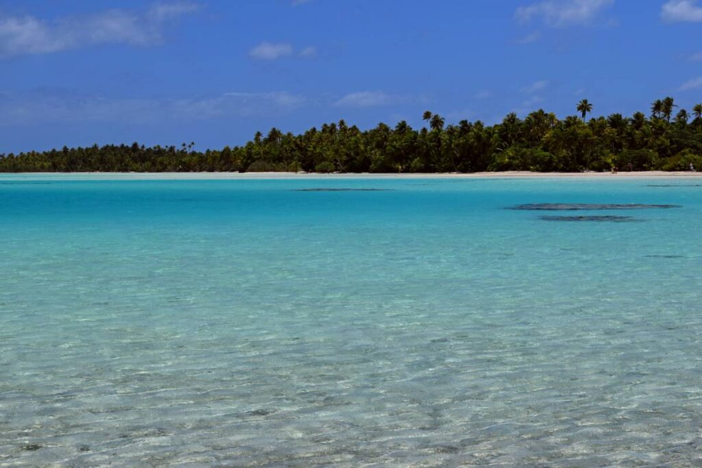 Orizzonte della Laguna Blu di Rangiroa con cielo azzurro e mare turchese separati dalle palme del motu