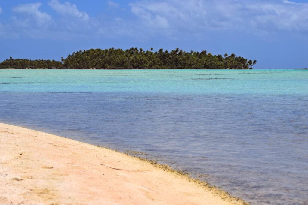 Vista sulla Laguna Blu di Rangiroa con sabbia bianca, mare dalle sfumature turchesi e palme sul motu