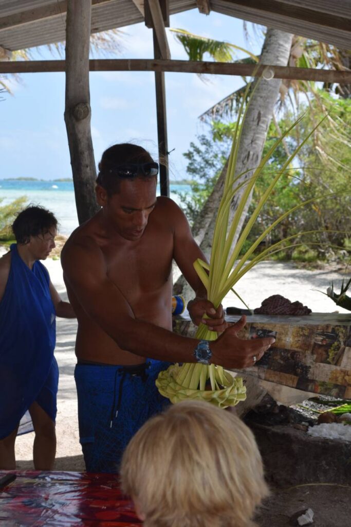 Accompagnatore alla Laguna Blu di Rangiroa che insegna a costruire un cappello con foglie di palma intrecciate