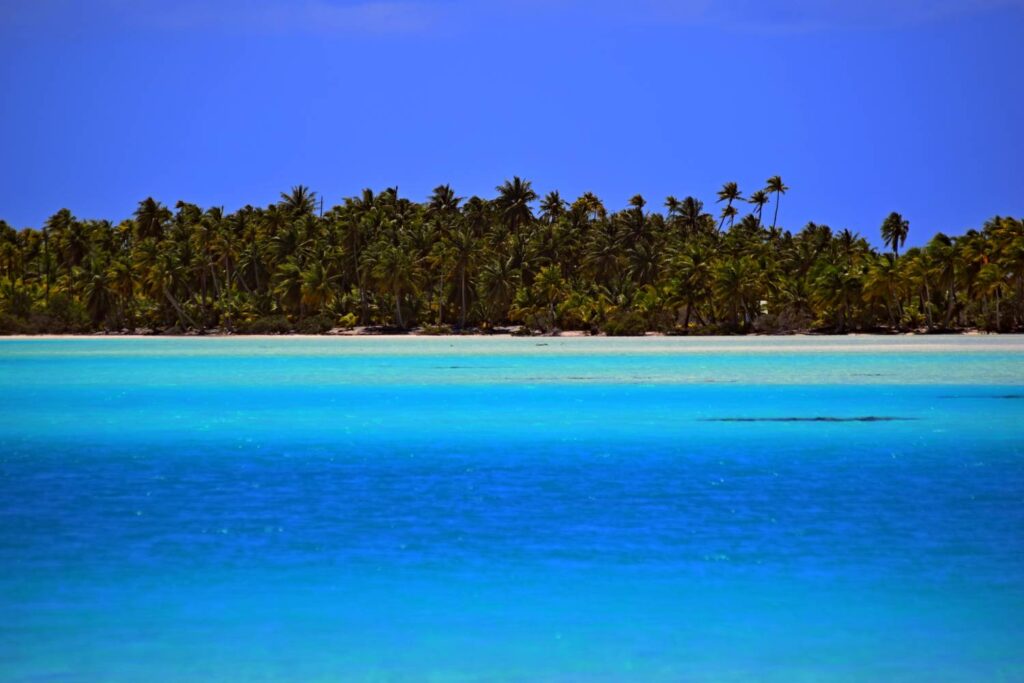 Laguna Blu di Rangiroa con mare dalle mille sfumature, lingua di sabbia bianca, palme sullo sfondo e cielo azzurro