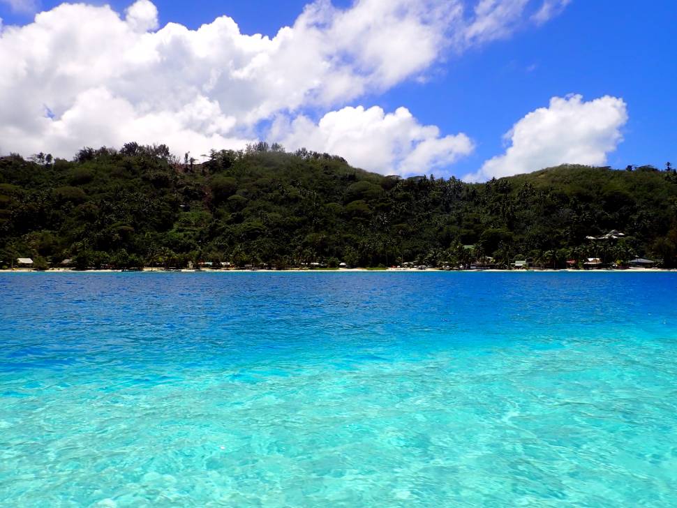 Laguna di Bora Bora vista dalla barca, con sfumature di azzurro e blu e vegetazione verde sullo sfondo