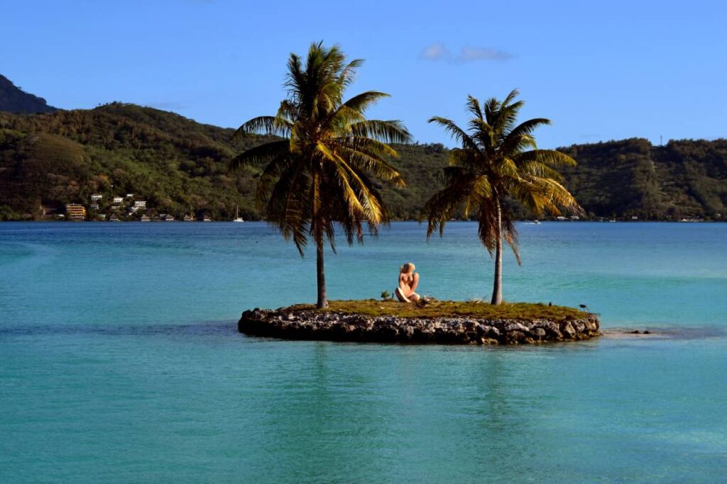 Motu di Bora Bora con due palme e una scultura sul mare