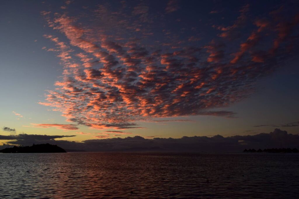 Nuvole rosa a pecorella durante il tramonto sulla laguna di Bora Bora, riflesse sulla superficie del mare