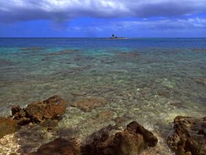 Oceano e cielo dalle mille sfumature che si incontrano all’orizzonte, con una piccola isola in lontananza a Rangiroa